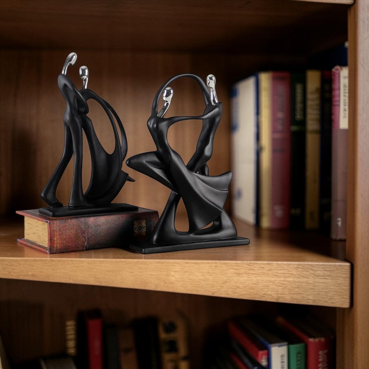 Abstract couple sculptures styles A and B displayed on a bookshelf