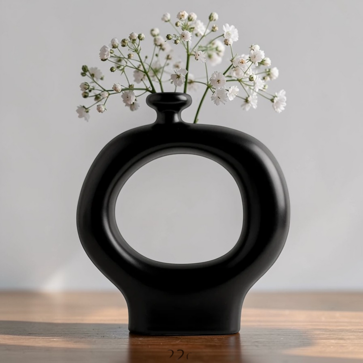 Black ceramic donut vase with white flowers