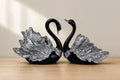 Black and silver swan figurine pair on a neutral background