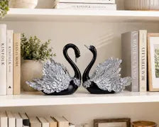 Black and silver swan figurines displayed on a shelf