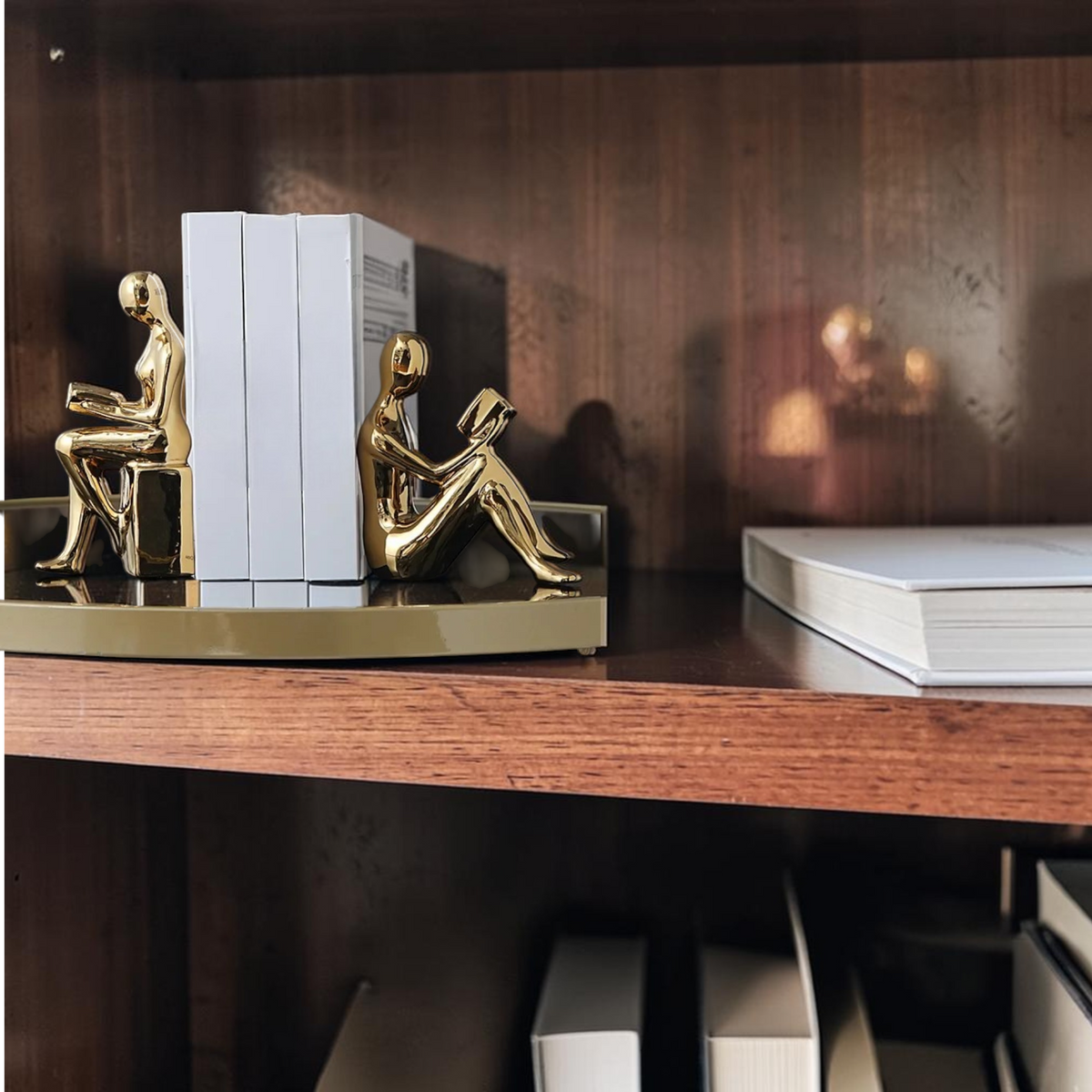 Gold reading figure bookends on a modern shelf