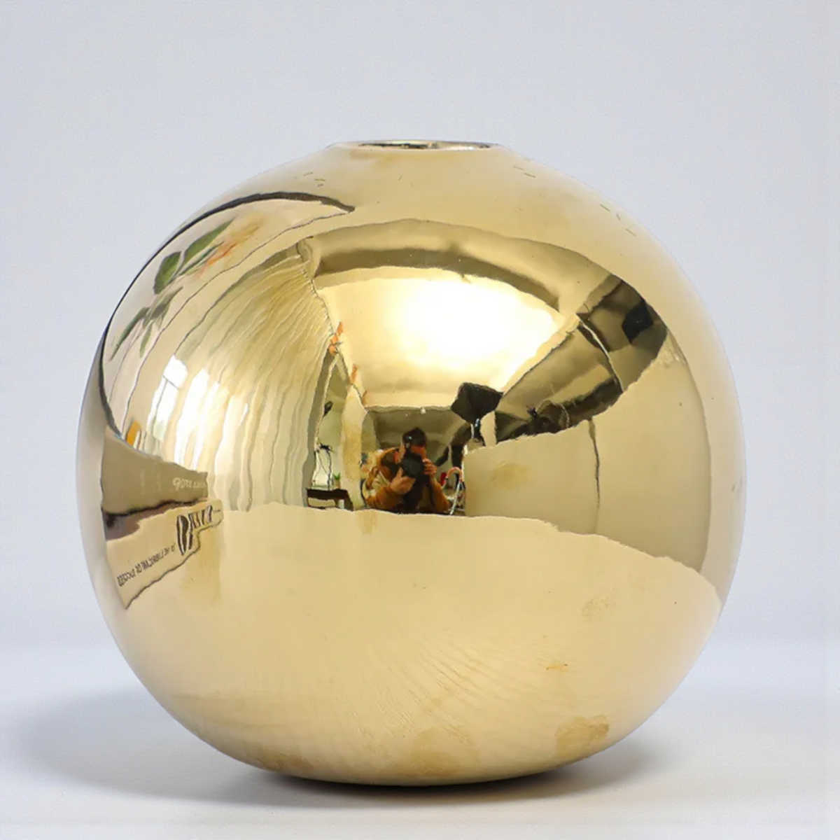Close-up of reflective gold sphere ceramic vase