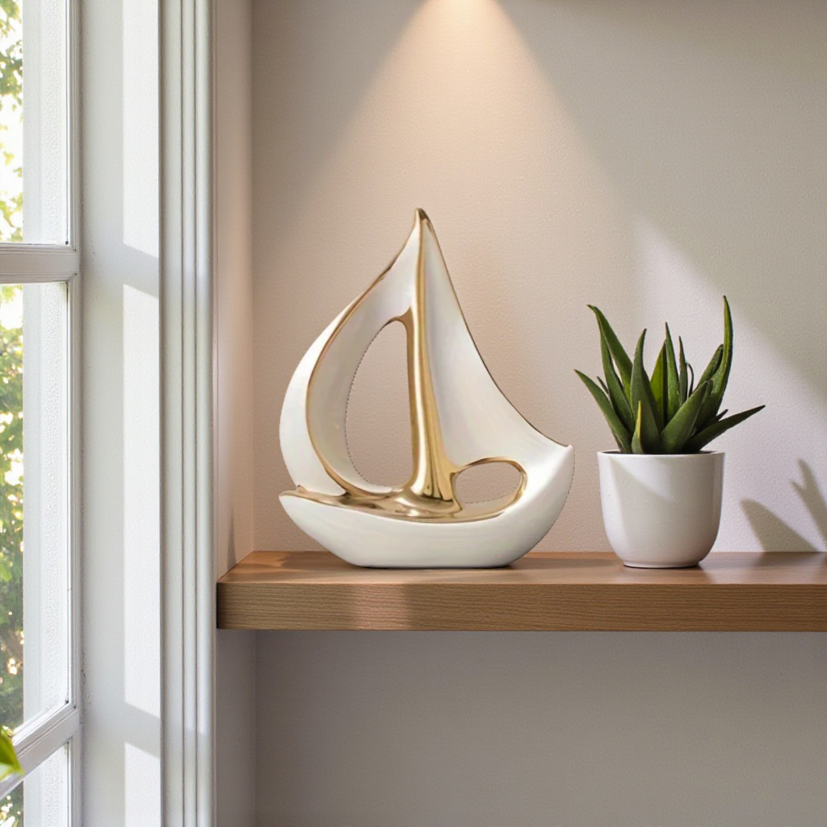 White and gold ceramic sailboat sculpture styled on a wooden shelf