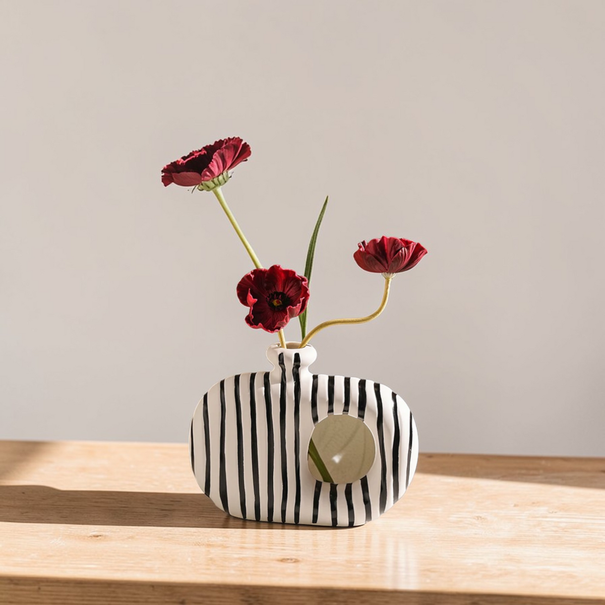 Striped ceramic donut vase with red flowers
