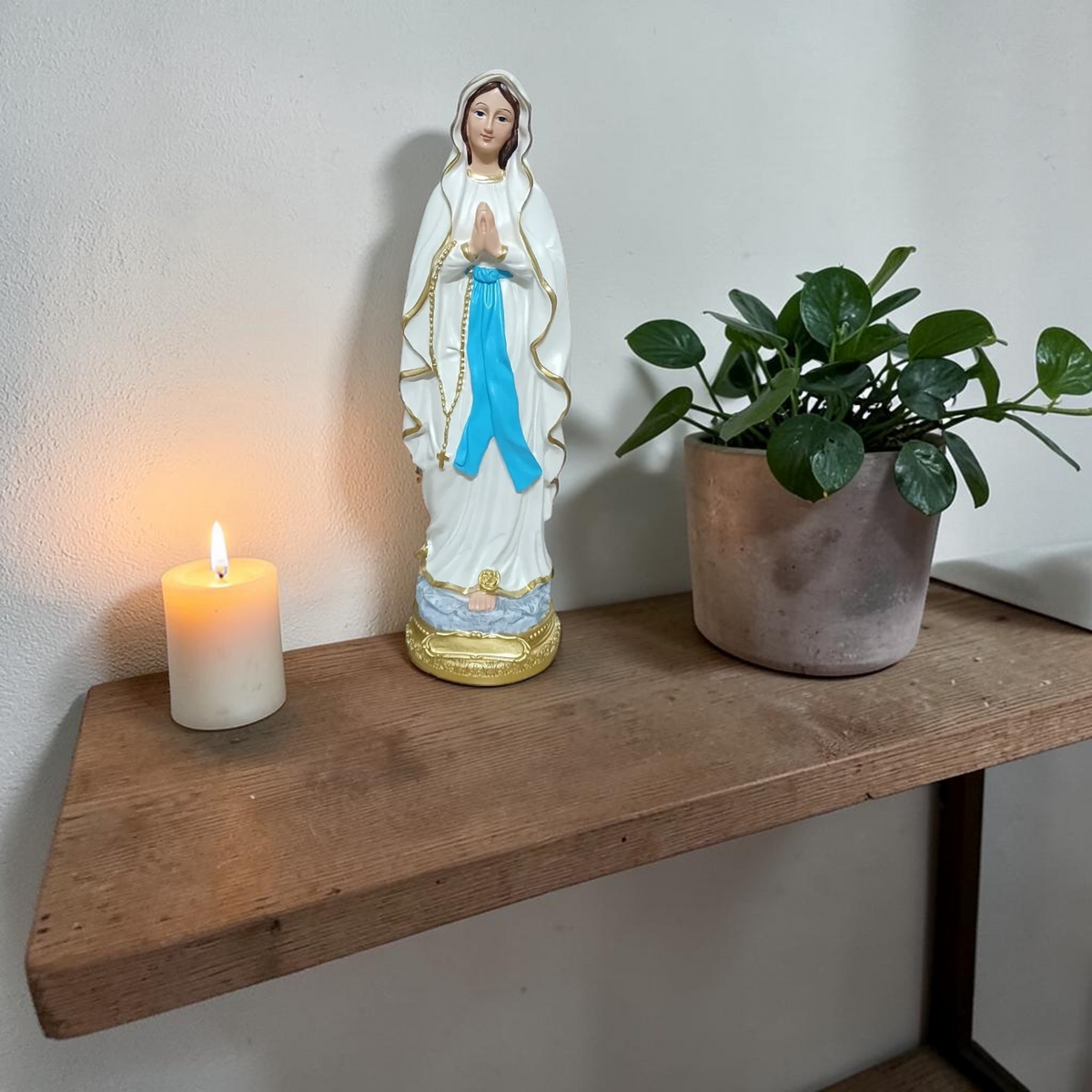 Virgin Mary statue with candle and plant